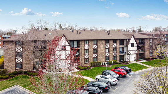Front view of a multi-story residential building with a brown brick facade and Tudor-style detailing.
