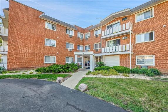 Front view of a three-story brick apartment building with balconies.