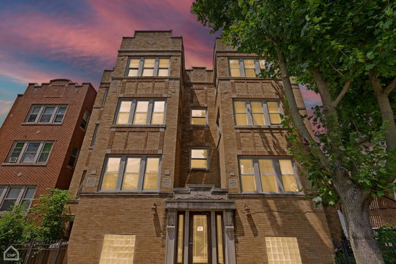 Front view of a multi-story brick building with large windows.