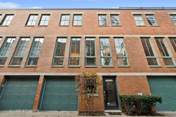 Front view of a multi-story brick building with green-framed windows and double garage doors.