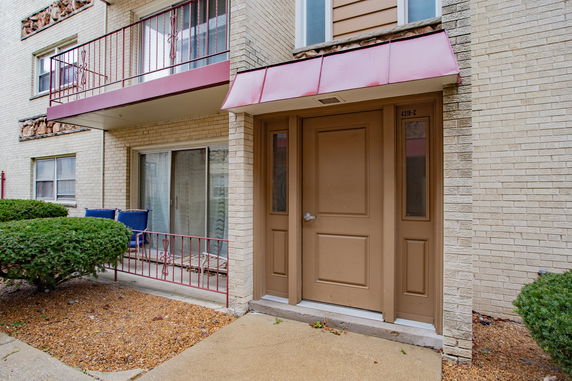 Front view of a brick apartment building with an entrance door and balcony.