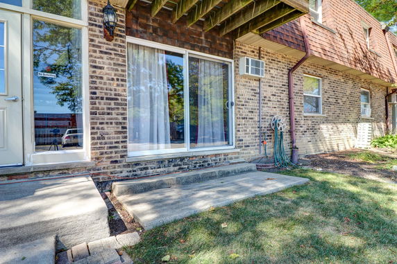 Back view of a brick house with sliding glass doors and a window air conditioner.