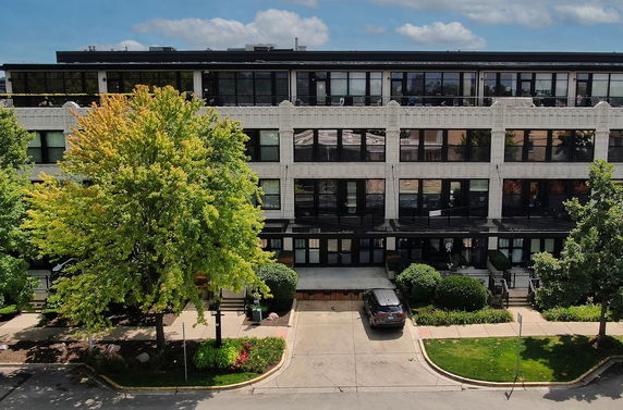 Front view of a multi-story building with large windows and a driveway.