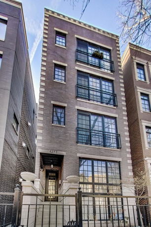 Front view of a multi-story residential building with large windows and a brick exterior.