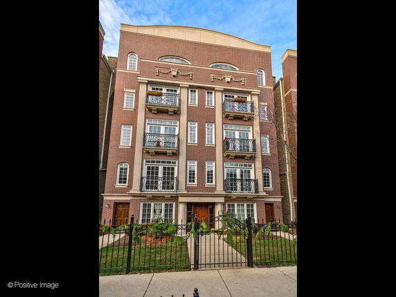 Front view of a multi-story brick apartment building with balconies.