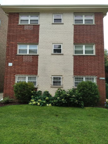 Front view of a three-story brick building with multiple windows.