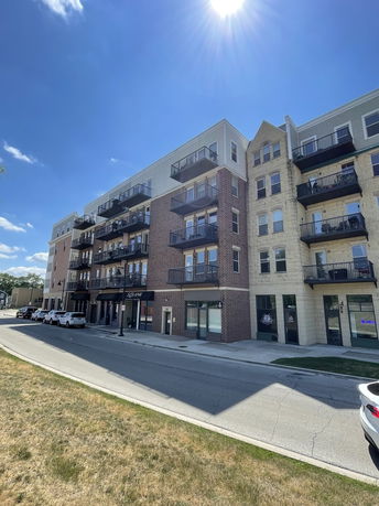 Front view of a multi-story residential building with balconies and street-level shops.