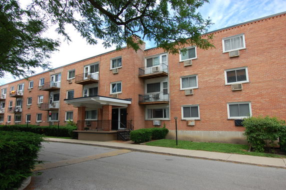 Front view of a multi-story brick apartment building with balconies.