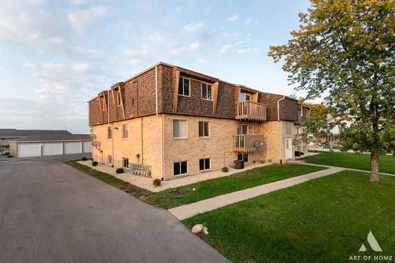 Front view of a multi-story residential building with brick facade and small balconies.
