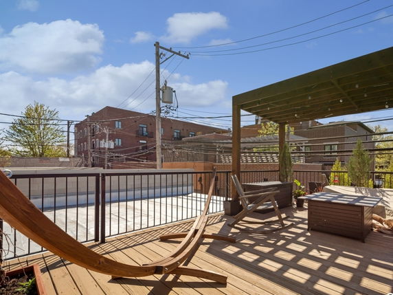 Rooftop patio with wooden furniture and pergola.