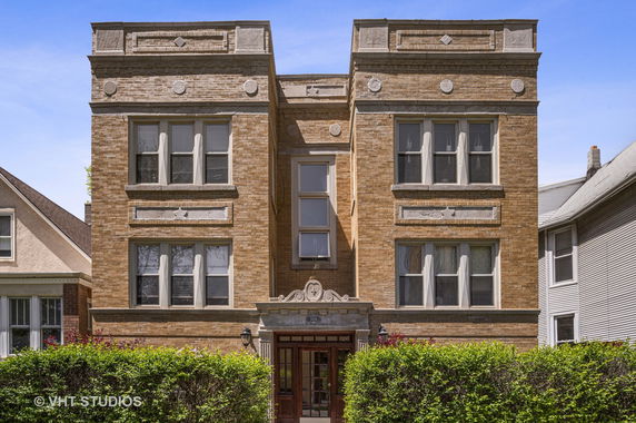 Front view of a multi-story brick building with decorative stone accents and multiple windows.