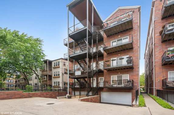 View of a multi-story brick apartment building with balconies and external staircases.