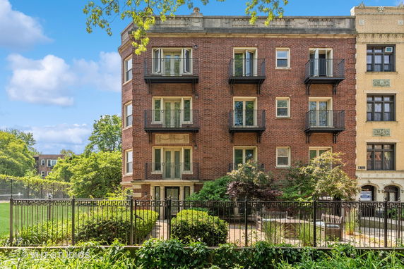 Front view of a multi-story brick apartment building with balconies.