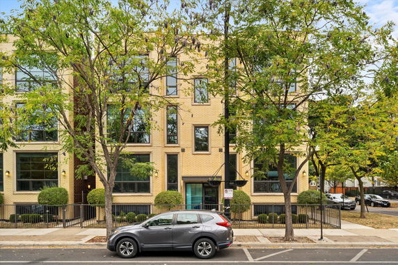 Front view of a multi-story brick building with large windows.