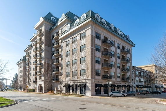 Front view of a multi-story residential building with balconies and decorative roof design.
