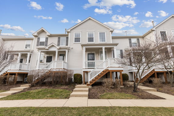 Front view of a two-story townhouse with white siding and elevated entrance.