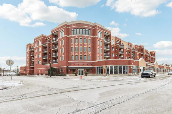 Front view of a multi-story brick apartment building with large windows and balconies.