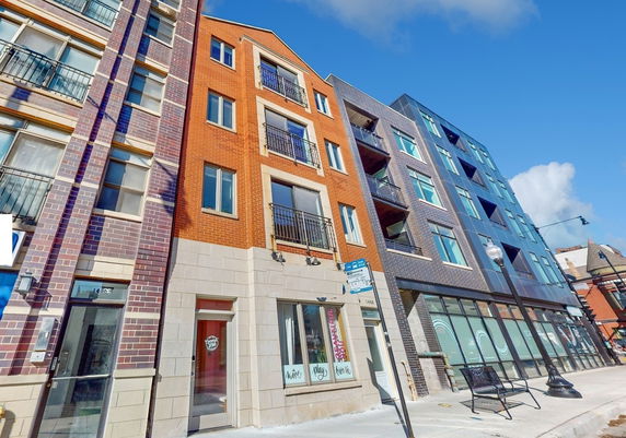 Street view of multi-story residential and commercial buildings with varying architectural styles.