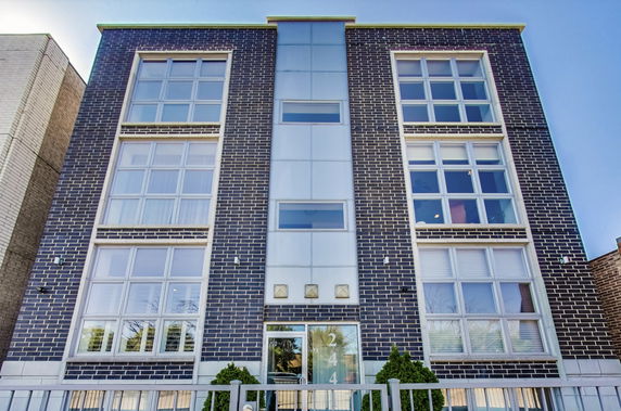 Front view of a modern multi-story brick building with large windows.