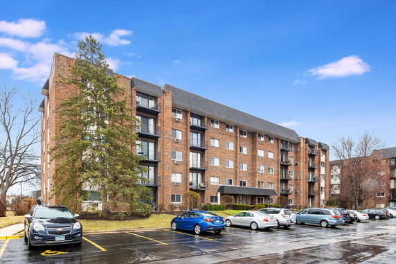 Front view of a multi-story brick apartment building with balconies.