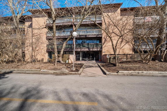 Front view of a multi-story brick building with balconies and a central entrance.