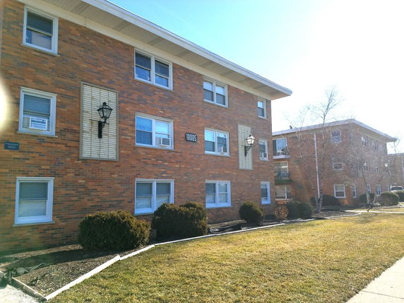 Front view of a brick multi-story apartment building.
