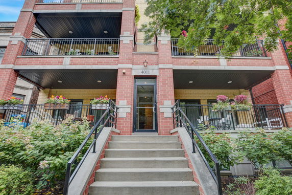 Front view of a multi-story brick building with balconies and flower decorations.