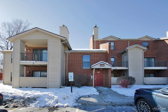 Front view of a multi-story brick apartment building with balconies and a main entrance.