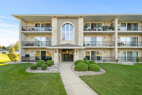 Front view of a three-story apartment building with multiple balconies.