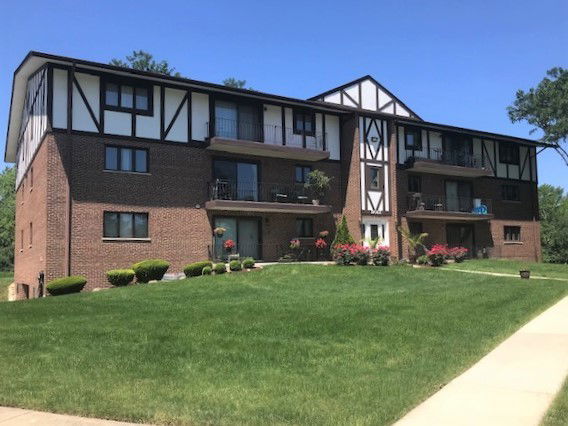 Front view of a three-story apartment building with brick facade and decorative timber accents.