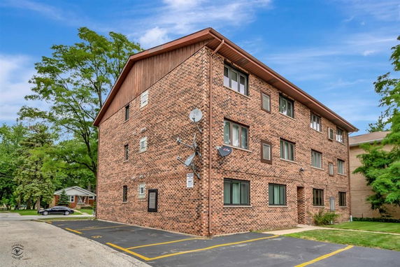 Front view of a multi-story brick building with multiple windows and satellite dishes.