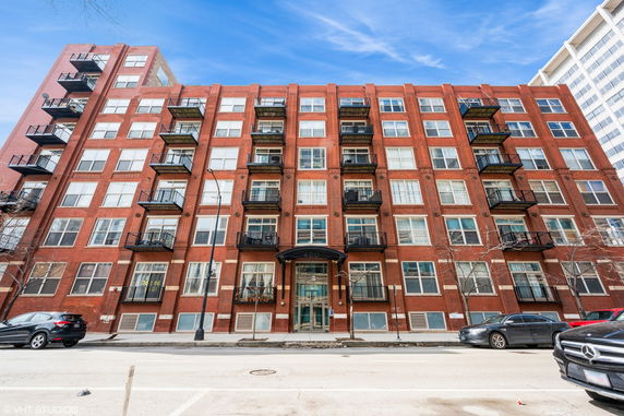 Front view of a multi-story brick apartment building with balconies.