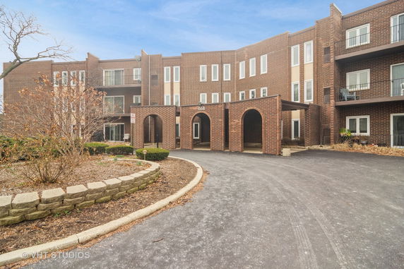 Front view of a multi-story brick building with an entrance featuring arches.
