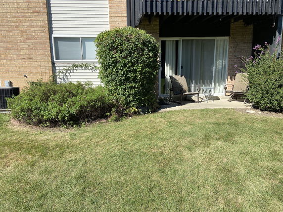 View of a house exterior with patio chairs and sliding glass door.