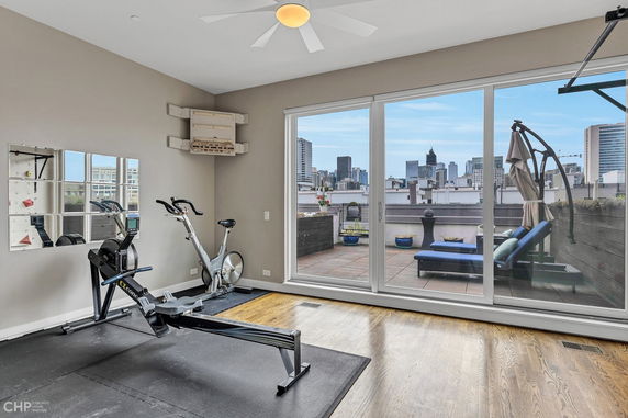 Indoor exercise area with equipment facing a window overlooking a rooftop terrace.