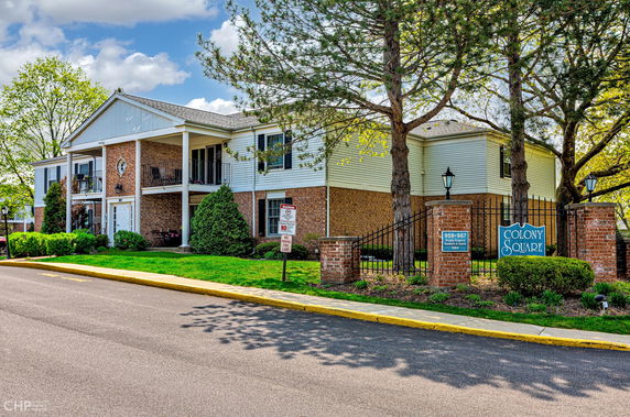 Front view of a two-story building with brick and siding exterior, featuring balconies and a gated entrance.