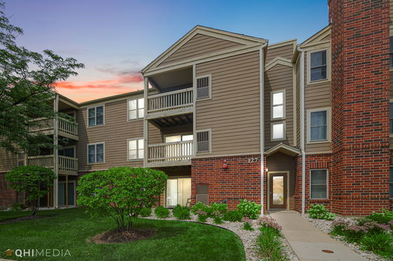 Front view of a three-story apartment building with brick and siding exterior.