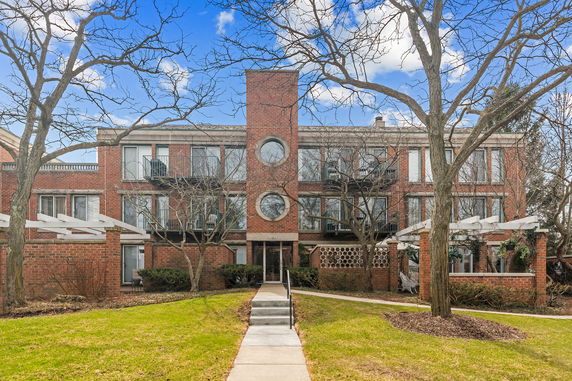 Front view of a three-story brick building with circular windows and balconies.