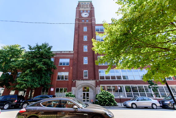 Front view of a multi-story red brick building with a clock tower.