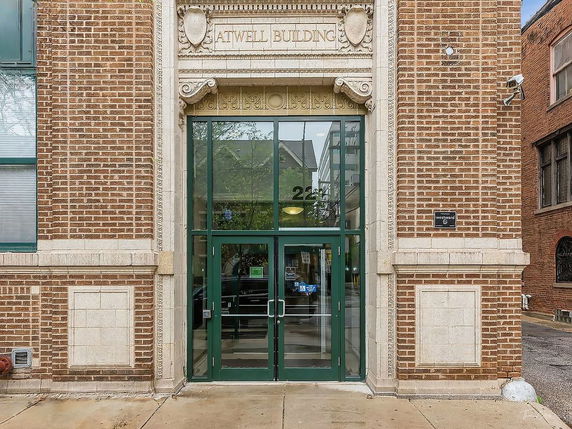 Front view of a brick building with a glass entrance and decorative stonework.
