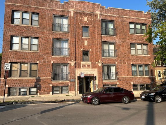 Front view of a three-story brick apartment building with multiple windows.