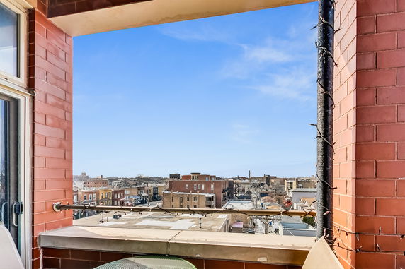 Panoramic view from a building balcony overlooking urban rooftops and skyline.