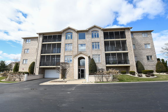 Front view of a multi-story apartment building with a central entrance and balconies.