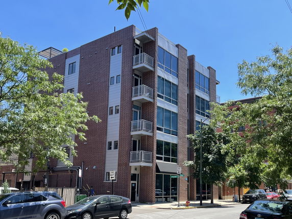 Front view of a multi-story brick building with large windows and balconies.