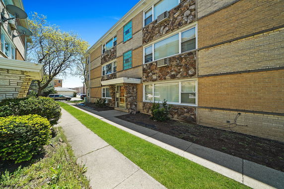 Front view of a three-story apartment building with stone and brick exterior.