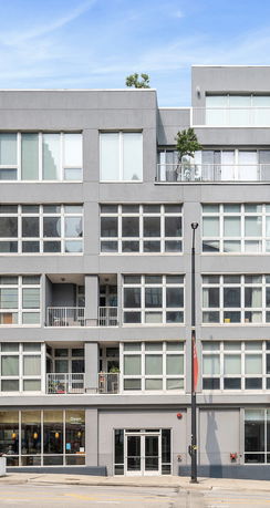 Front view of a modern multi-story building with large windows and a minimalist design.