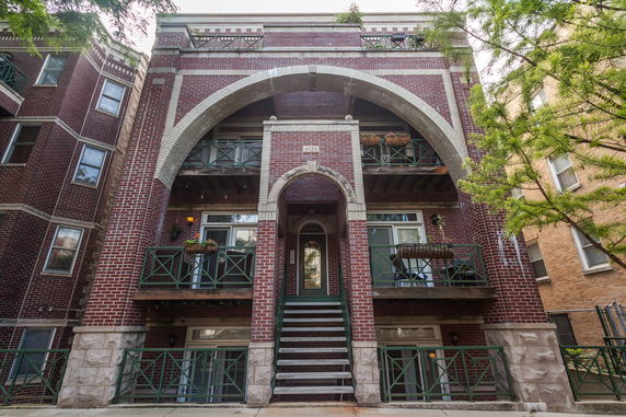 Front view of a multi-story brick building with arched entrance.
