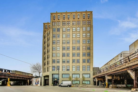 Front view of a multistory building with a beige facade, windows, and entrance at street level.