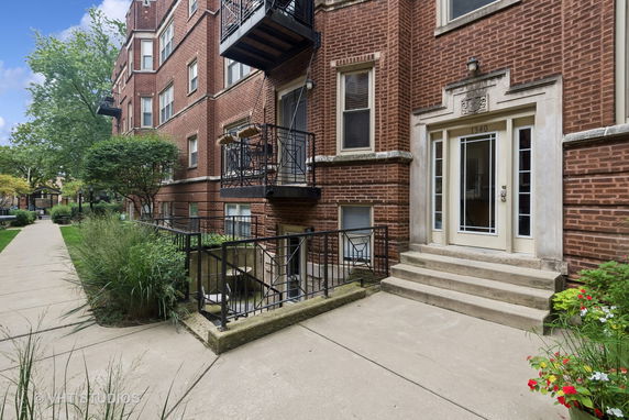 Front view of a multi-story brick building with balconies and a glass door entrance.