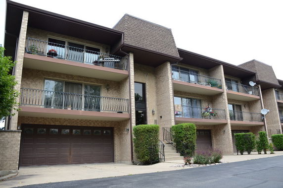 Front view of a multi-story residential building with balconies and garages.